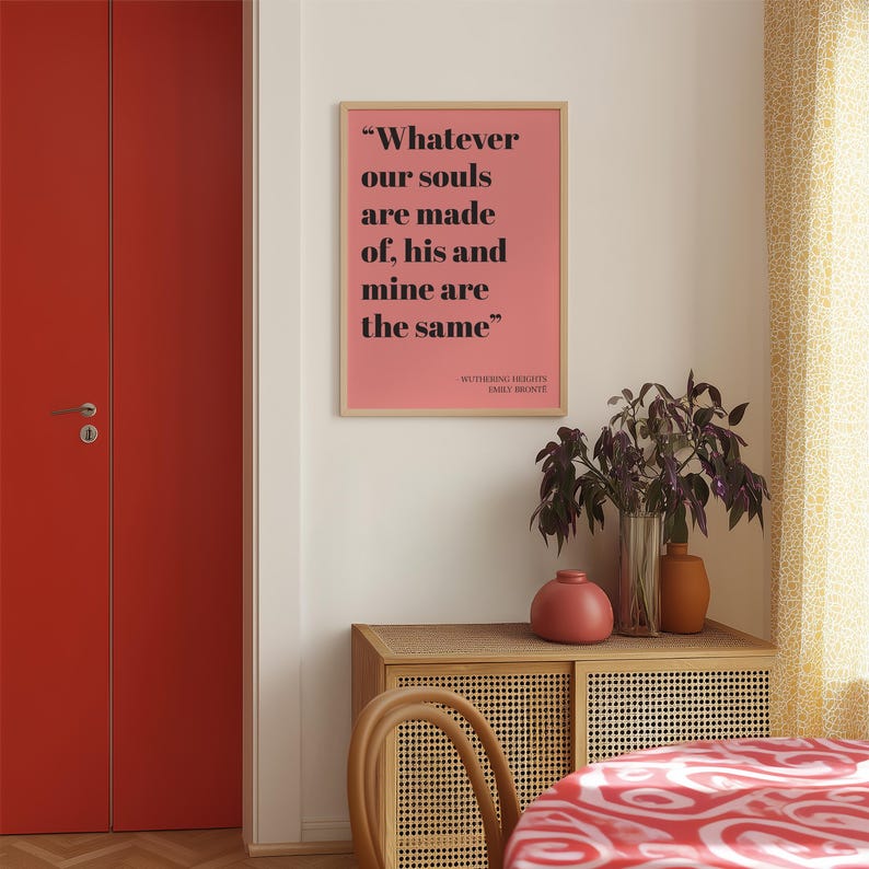 Op de afbeelding: Een rechthoekige wandkunstprint in een lichthouten lijst met een zalmroze achtergrond en zwarte tekst die luidt: "Whatever our souls are made of, his and mine are the same" gevolgd door "WUTHERING HEIGHTS EMILY BRONT&Euml;".
