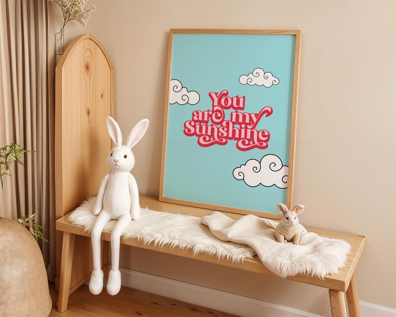 May include: A framed print with a blue background and white clouds. The print features the text "You are my sunshine" in red and pink letters.