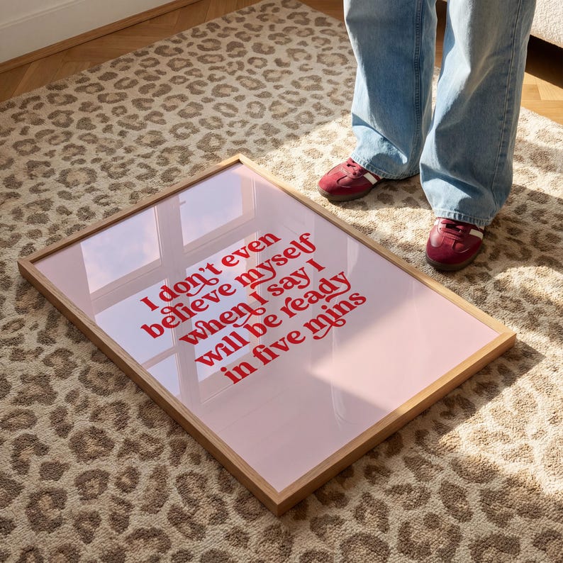 K&ouml;nnte beinhalten: Ein rechteckiges gerahmtes Wandbild mit hellrosa Hintergrund und fettgedrucktem rotem Text: I don't even believe myself when I say I will be ready in five mins. Der Rahmen besteht aus hellem Holz und hat eine reflektierende Glasoberfl&auml;che.