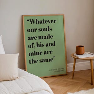 Op de afbeelding: Een rechthoekige ingelijste wandprint met een saliegroene achtergrond en zwarte schreefletters met de tekst "Whatever our souls are made of, his and mine are the same", gevolgd door "WUTHERING HEIGHTS EMILY BRONT&Euml;" in een kleiner lettertype.