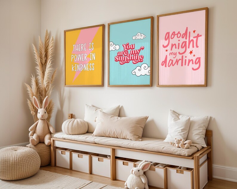May include: Three framed prints with colorful backgrounds and white text. The prints are hanging on a white wall above a wooden bench with storage bins. The prints read "There is power in kindness", "You are my sunshine", and "Good night my darling".