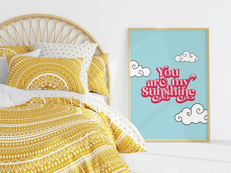 May include: A framed print with a blue background and white clouds. The text "You are my Sunshine" is written in pink with a retro font.