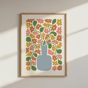 May include: A framed art print featuring a stylized floral arrangement. A light blue vase holds stems with green leaves and orange, pink, and yellow flowers. The artwork is set against a cream background and framed in a light wood.