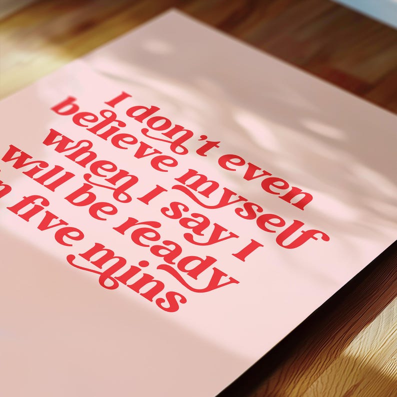 K&ouml;nnte beinhalten: Ein rechteckiger Druck auf hellrosa Hintergrund mit fettgedrucktem rotem Text, der lautet: I don't even believe myself when I say I will be ready in five mins. Die Typografie ist mit dekorativen Schn&ouml;rkeln an den Buchstaben gestaltet.