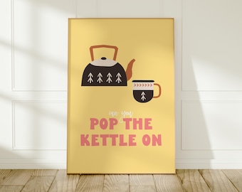 May include: A framed poster with a yellow background features a black and brown teapot and a matching mug. The text "can you POP THE KETTLE ON" is in pink. The artwork is displayed on a wooden floor.