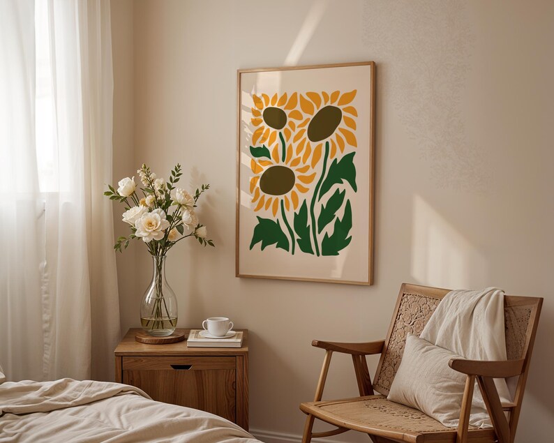 May include: A framed art print featuring a stylized illustration of sunflowers in yellow, green, and brown. The artwork hangs on a beige wall above a wooden chair and a nightstand with a vase of flowers.