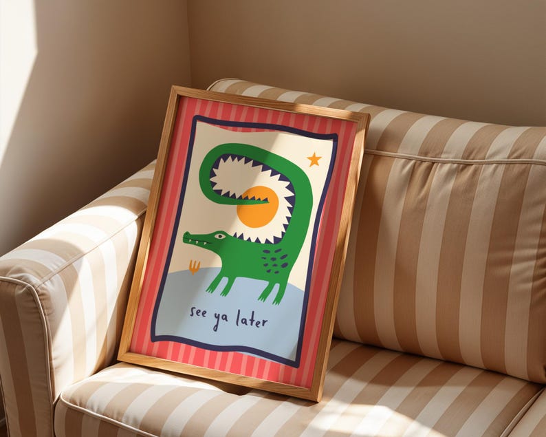Pu&ograve; includere: Una stampa rettangolare incorniciata raffigurante un coccodrillo verde con la coda curva, un sole giallo e una piccola stella arancione. L'illustrazione include il testo "see ya later" in blu scuro su uno sfondo a righe verticali rosa e rosse.