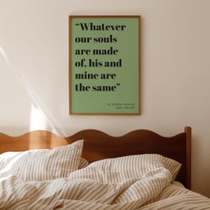 Op de afbeelding: Een rechthoekige wandkunstprint in een houten lijst met een saliegroene achtergrond en zwarte schreefletters met de tekst: "Whatever our souls are made of, his and mine are the same", gevolgd door "Wuthering Heights" en "Emily Bronte".
