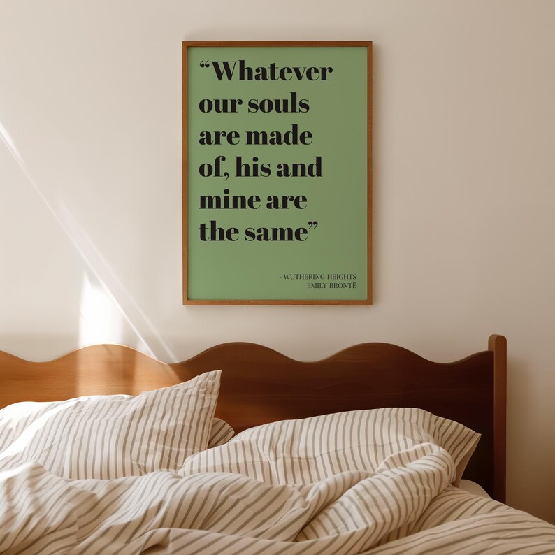 Op de afbeelding: Een rechthoekige wandkunstprint in een houten lijst met een saliegroene achtergrond en zwarte schreefletters met de tekst: "Whatever our souls are made of, his and mine are the same", gevolgd door "Wuthering Heights" en "Emily Bronte".