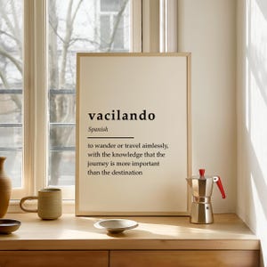 Puede incluir: Un p&oacute;ster beige con marco negro y la palabra "vacilando" en negrita negra. La palabra se define como "vagar o viajar sin rumbo, con el conocimiento de que el viaje es m&aacute;s importante que el destino".