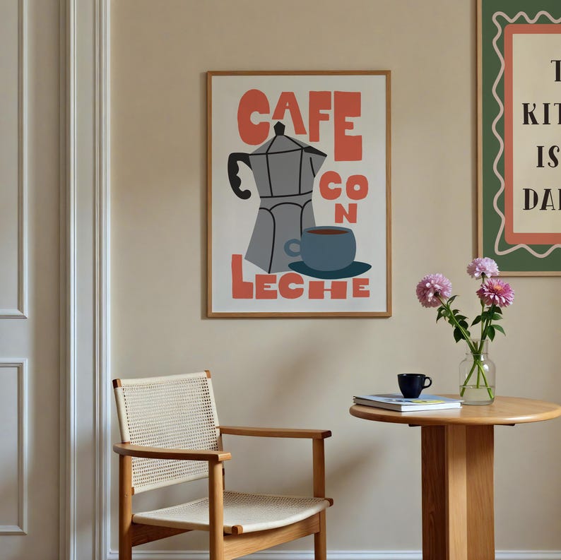 May include: A framed art print with a coffee theme. The print features the words "CAFE CON LECHE" in coral-colored block letters, along with a gray coffee maker and a blue cup of coffee. The print is in a wooden frame.