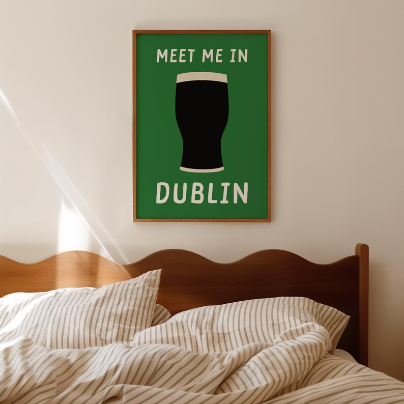 May include: A framed poster with a green background and a black pint of stout illustration. The text "MEET ME IN" is above the pint, and "DUBLIN" is below it, all in white. The frame is brown.