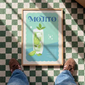 May include: A framed print featuring a Mojito cocktail illustration. The artwork showcases a tall glass filled with ice, lime slices, and mint, with the word "Mojito" in stylized blue lettering. The background is a light teal color.