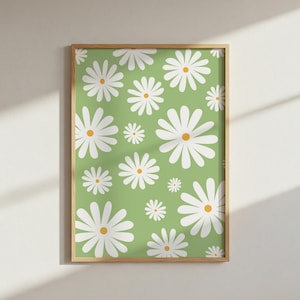May include: A framed print with a repeating pattern of white daisies with yellow centres on a light green background. The daisies vary in size and are evenly spaced. The frame is a light brown colour.