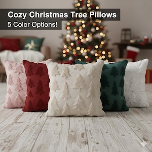 Può includere: Cinque cuscini quadrati in vari colori: rosa chiaro, bordeaux, crema, verde scuro e bianco. Ogni cuscino presenta un design ad albero di Natale strutturato. I cuscini sono disposti su un pavimento in legno con un albero di Natale sullo sfondo.