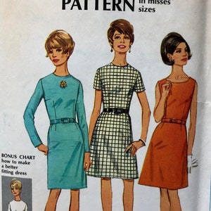 Könnte beinhalten: Vintage Simplicity Schnittmuster Nummer 7500 für ein Damenkleid. Das Schnittmuster ist für ein Bonus-Basis-Schnittmuster in den Größen 6-8-10-12-14-16-18. Das Schnittmuster zeigt drei Frauen, die verschiedene Versionen des Kleides tragen: ein türkisfarbenes Kleid, ein kariertes Kleid und ein rostfarbenes Kleid.