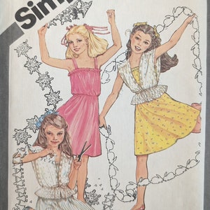 May include: Simplicity sewing pattern number 9938 for girls' dresses. The pattern includes two sizes, 7 and 8. The pattern cover features three girls wearing different dresses, one in pink, one in yellow, and one in white. The pattern is titled "Cinderella" and includes a trademark symbol.