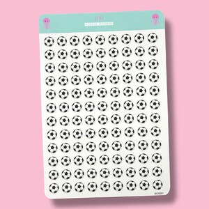 May include: A sheet of stickers featuring numerous black and white soccer ball designs. The stickers are arranged in neat rows and columns on a white background. The top of the sheet has a light teal banner with the text "jelly studio designs" and a small pink jellyfish illustration.