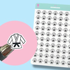 May include: Sheet of stickers featuring a white karate gi with a black belt. The stickers are on a white background with a light blue background. A single sticker is on a pink circle. The sheet has the text "jelly studio designs".