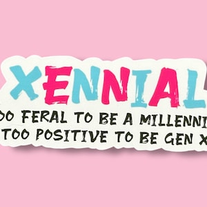 May include: A white sticker with the word "Xennial" in pink and blue lettering. The text below reads "Too feral to be a millennial, too positive to be Gen X."