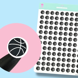 May include: Sheet of basketball stickers with a black and white design. The stickers are round and feature a basketball graphic. The background is light blue and pink. The stickers are from Jelly Studio Designs.