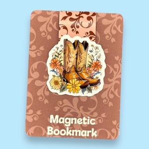 May include: A brown and pink magnetic bookmark with a floral design featuring a pair of brown cowboy boots. The text "Magnetic Bookmark" is printed on the bookmark.