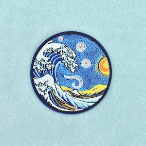 Pode incluir: Um emblema bordado circular apresentando uma fusão de estilos artísticos, retratando uma grande onda azul com crista branca, um sol amarelo e estrelas giratórias contra um céu azul escuro, tudo dentro de uma borda costurada em azul escuro.