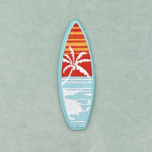 Peut inclure: Un écusson brodé en forme de planche de surf avec une bordure bleu clair. Le motif représente la silhouette d'un palmier blanc sur un ciel rouge et orange au coucher du soleil, au-dessus d'un océan bleu clair avec des vagues blanches.