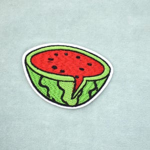 Peut inclure: Écusson brodé représentant une demi-pastèque. L'écusson a un intérieur rouge avec des graines noires, une peau verte et un bord blanc. La pastèque est coupée, avec une petite section de l'intérieur rouge qui dégouline.