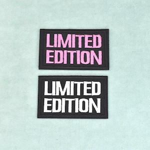 May include: Two rectangular embroidered patches with black fabric backgrounds. The top patch features the text LIMITED EDITION in pink thread, while the bottom patch features the same text in white thread. Both patches have a black border.