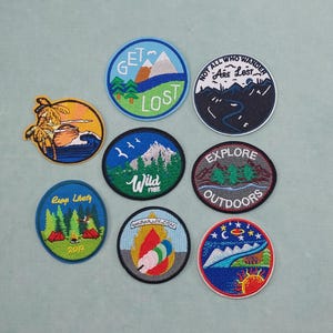 Peut inclure: Huit patchs brodés thermocollants sur le thème de la nature et des activités de plein air. Les patchs présentent des motifs tels que des montagnes, des arbres, un feu de camp, un coucher de soleil, un palmier et une rivière. Les patchs sont tous circulaires et ont un fond blanc avec des broderies colorées.