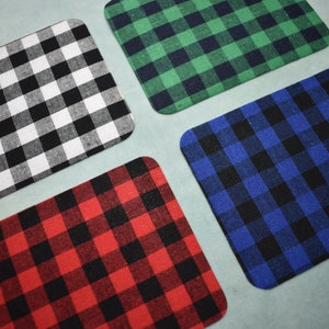 Puede incluir: Cuatro cuadrados de tela con un patr&oacute;n a cuadros. Los cuadrados son blanco y negro, rojo y negro, azul y negro, y verde y negro.