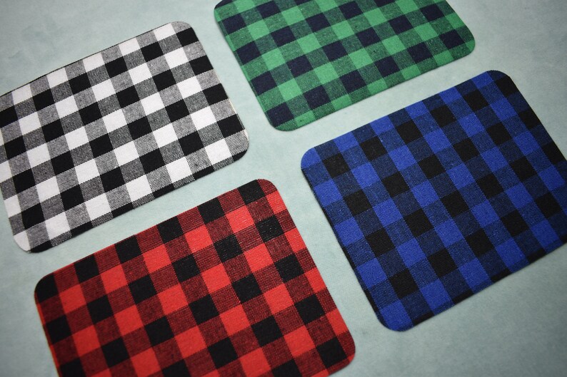 Puede incluir: Cuatro cuadrados de tela con un patr&oacute;n a cuadros. Los cuadrados son blanco y negro, rojo y negro, azul y negro, y verde y negro.