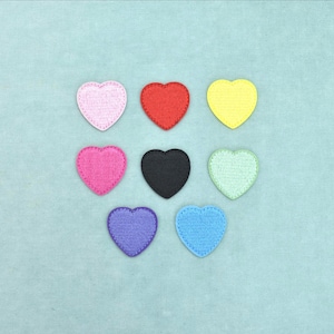 Può includere: Una collezione di otto toppe ricamate a forma di cuore disposte in una griglia. Le toppe presentano una varietà di colori solidi, tra cui rosa chiaro, rosso, giallo, rosa acceso, nero, verde chiaro, viola e azzurro con finitura testurizzata.
