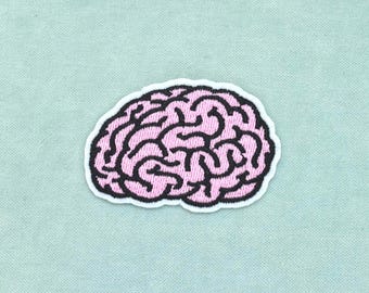May include: An embroidered patch in the shape of a human brain. The design features light pink thread for the brain tissue and thick black thread for the intricate, winding sulci and gyri patterns, all outlined with a clean white border.