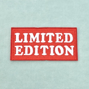 Peut inclure: Un écusson rectangulaire brodé avec un fond rouge et une bordure rouge épaisse. Le texte LIMITED EDITION est cousu en lettres capitales blanches et grasses au centre de l'écusson, avec une police de caractères sans empattement très nette.