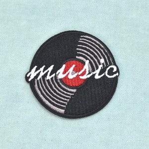 Può includere: Una toppa ricamata circolare con il design di un disco in vinile nero e un'etichetta centrale rossa. La parola music è ricamata al centro in corsivo bianco. La toppa presenta un bordo nero e dettagli dei solchi in filo bianco.