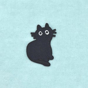 Op de afbeelding: Een geborduurde patch met het silhouet van een effen zwarte kat met een rond lichaam, puntige oren en drie snorharen aan elke kant. De kat heeft twee grote, ronde witte ogen met zwarte pupillen, wat zorgt voor een verbaasde uitdrukking.