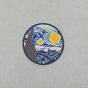 Può includere: Toppa ricamata raffigurante "Notte stellata" di Van Gogh. La toppa circolare ha un bordo blu scuro, con un cielo notturno nei toni del blu, giallo e bianco. Raffigura il cielo vorticoso e il villaggio.