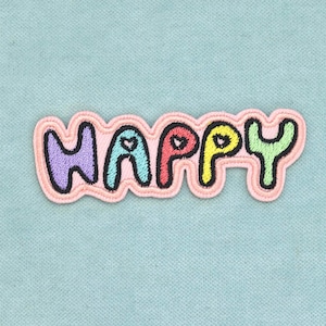 Puede incluir: Un parche bordado termoadhesivo con la palabra HAPPY en letras redondeadas, coloridas y abombadas. Cada letra está delineada en negro y rellena con un color pastel diferente, incluyendo morado, azul, rojo, amarillo y verde, sobre un fondo rosa.