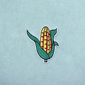 Aplique termocolante bordado com tema de milho e aplique de frutas cítricas para personalização.