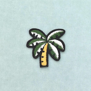 Puede incluir: Un parche bordado termoadhesivo con forma de palmera. El árbol presenta un tronco amarillo con marcas horizontales negras y frondas de color verde oscuro con reflejos blancos, todo ello delineado por un grueso borde negro sobre fondo azul claro.