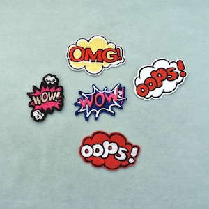 May include: Five embroidered patches featuring comic book style speech bubbles. The patches include the text OMG in yellow, WOW in pink and blue, OOPS in red and white, and WOW in pink and black, all designed with bold outlines and vibrant colors.