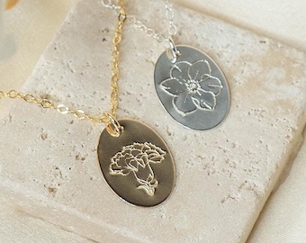 May include: Two delicate necklaces with oval pendants featuring engraved floral designs. One pendant is gold with a carnation design, the other is silver with a flower design.