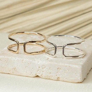 May include: A set of three ceramic mugs with a speckled, matte finish. The mugs are in shades of cream, light gray, and dark gray. Each mug has a simple, minimalist design and a rounded handle.