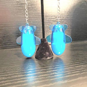 May include: A pair of blue airplane-shaped earrings with silver chains.