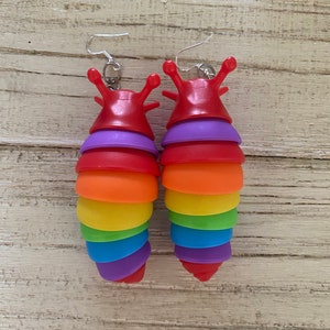 May include: A pair of rainbow-colored slug earrings. The earrings are made of plastic and have a silver hook.