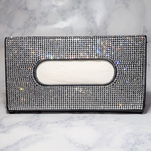 May include: A black tissue box cover with a rectangular opening and a design of small, clear rhinestones.