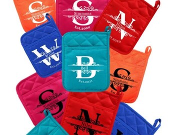May include: Nine personalized pot holders with different colors and names. The pot holders are quilted and have a hanging loop. The names are printed in black and white with a decorative flourish. The names are: Simmons, Niles, Willis, and Bell. The dates are: Est. 2020 and Est. 2021.