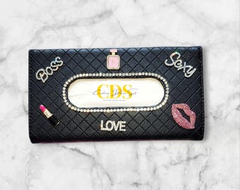 May include: Black quilted tissue box cover with rhinestone accents. Embellished with the words "Boss", "Sexy", and "Love". Features a lipstick, perfume bottle, and a pair of lips. The center has the text "CDS DECOR SPECIALIST".